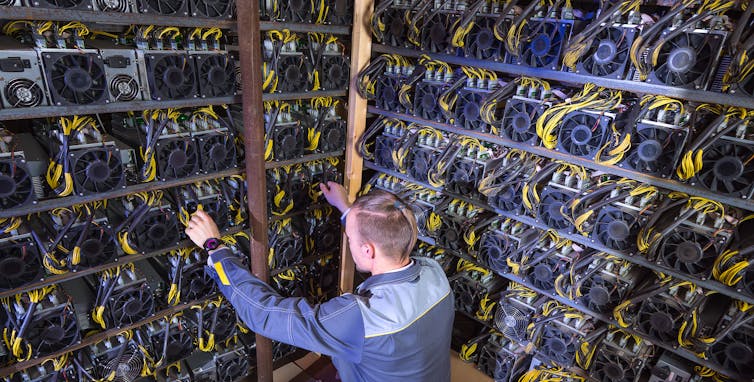 An engineer adjusts cables on a wall of servers.