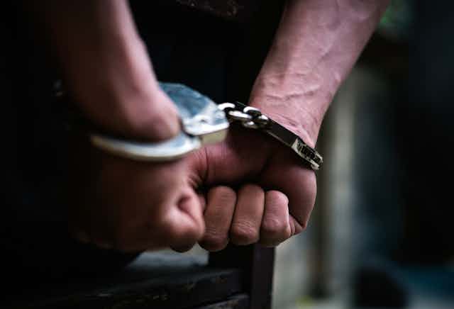 Close up of a man's hands handcuffed behind his back