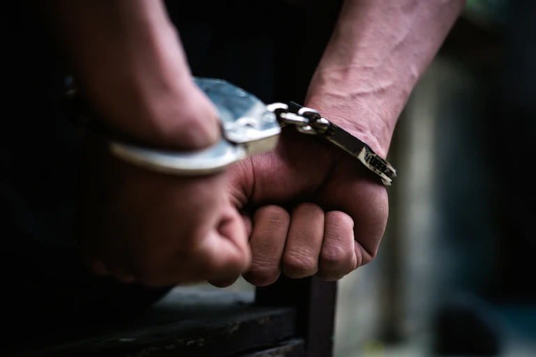 Close up of a man's hands handcuffed behind his back