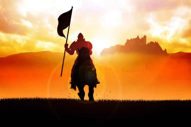 Silhouette of a medieval knight on horse carrying a flag against a sunset background