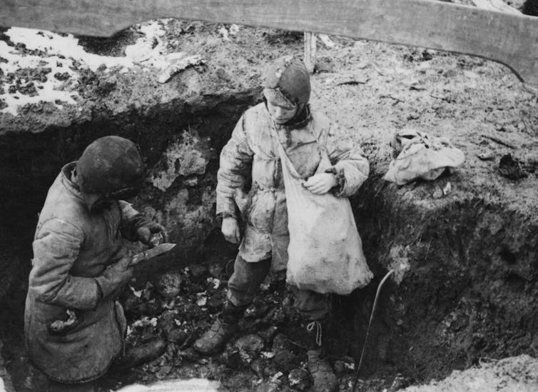 A black and white photo shows two boys in a pit outside, with a bag full of potatoes.