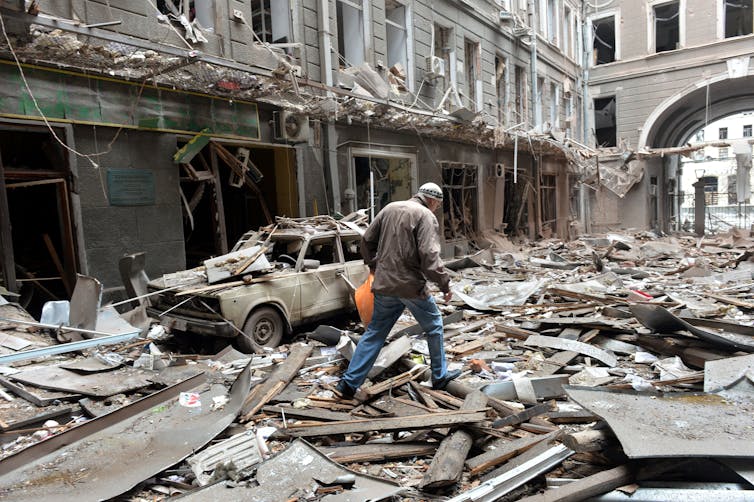 A man walks down a street covered in rubble and debris.