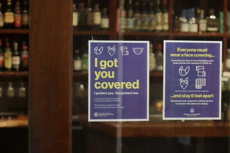 Two signs explaining mask requirements on the door of a restaurant.