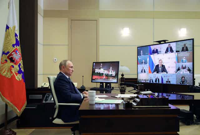 A man attends a virtual meeting while sitting at his desk.