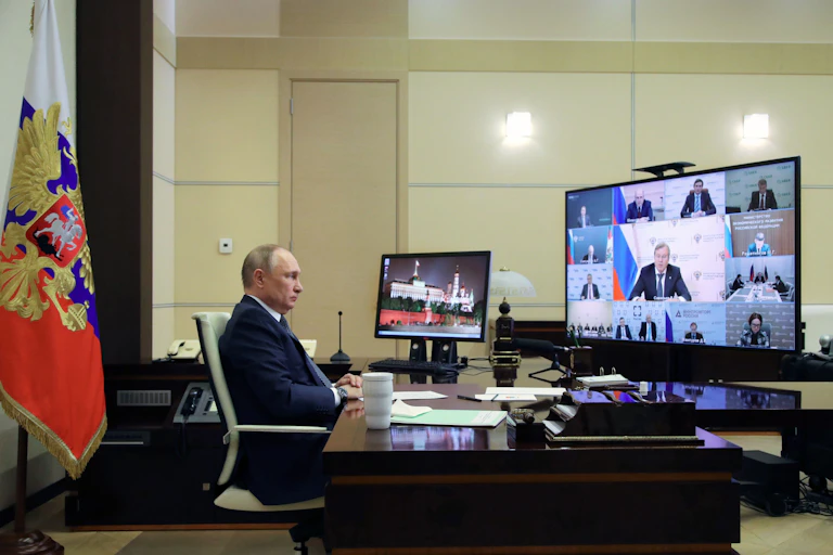 A man attends a virtual meeting while sitting at his desk.