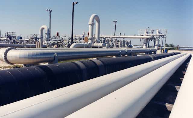 White and black pipes holding oil sit next to other piping gear at an oil repository
