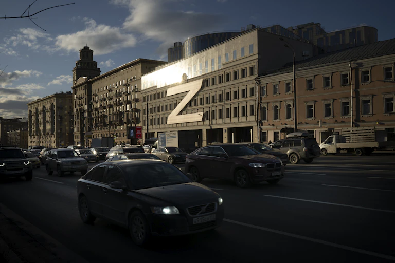 car drives past a building with a giant letter Z on it as the sun sets