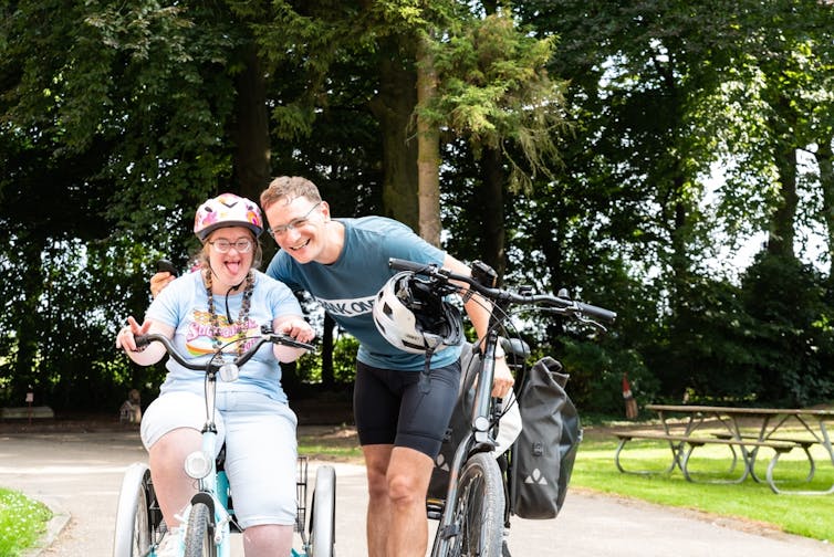 A woman and man with intellectual disability ride bikes along a path.