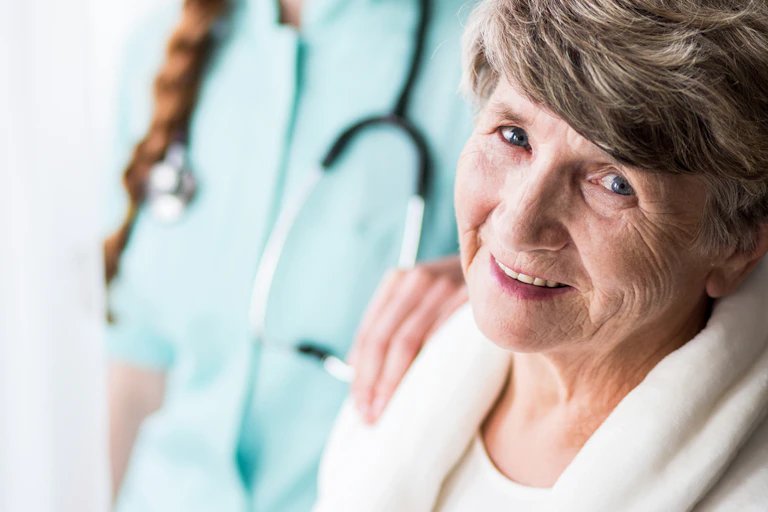 Doctor or nurse standing behind elderly lady with hand on shoulder
