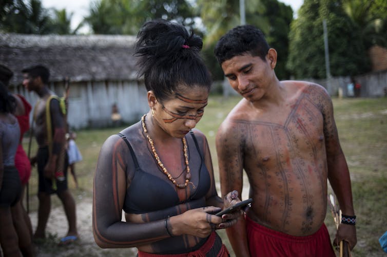 woman looks at phone, man looks on