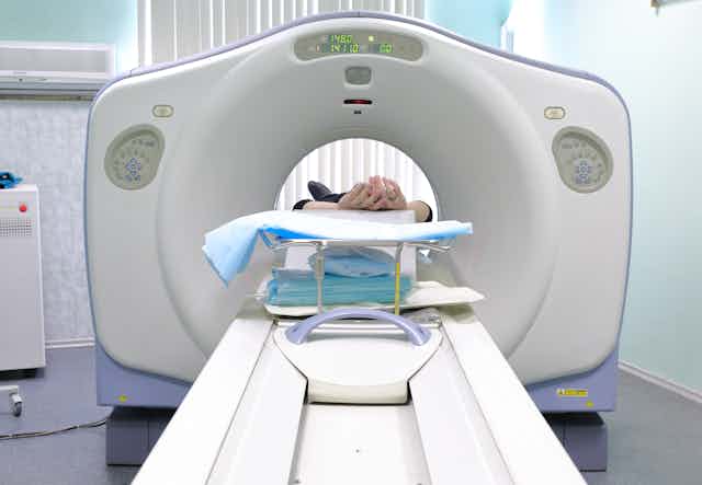 A CT machine with a patient's hands visible