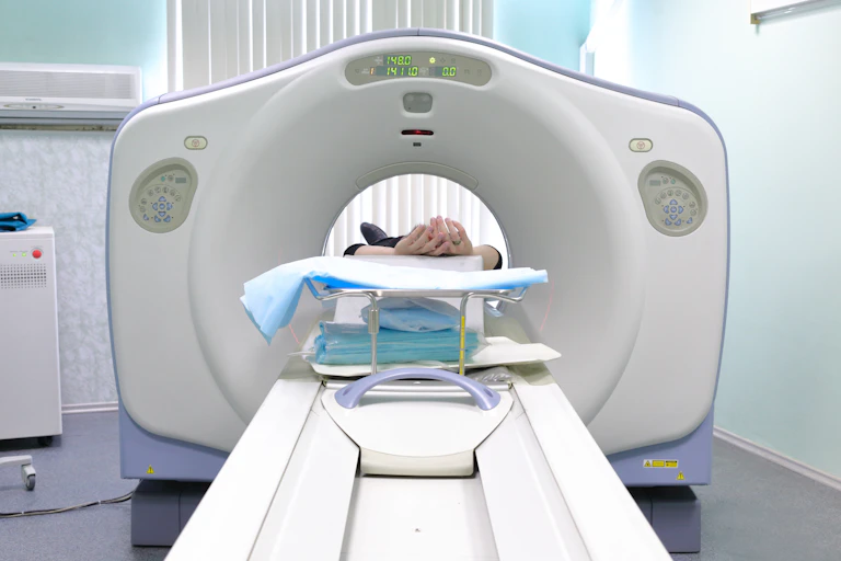 A CT machine with a patient's hands visible