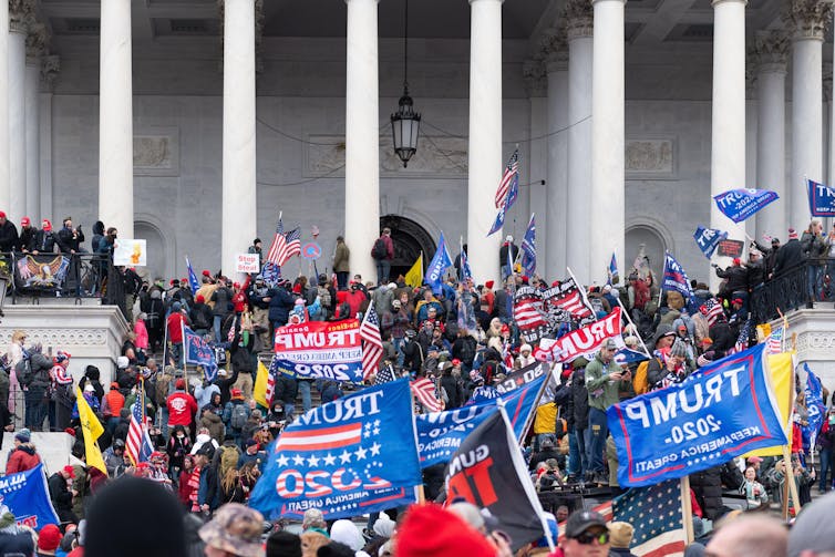 A crowd carrying blue and red banners on the steps of the US Capitol building.