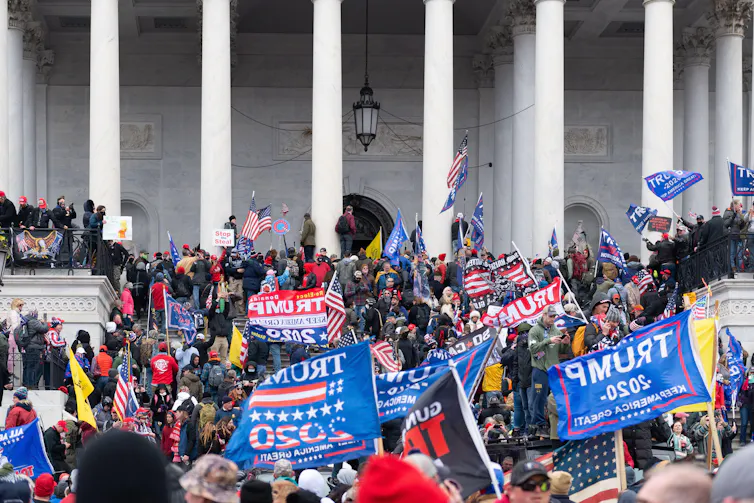 A crowd carrying blue and red banners on the steps of the US Capitol building.