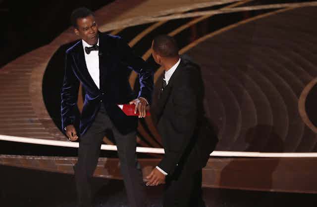 Two men in suits on stage.