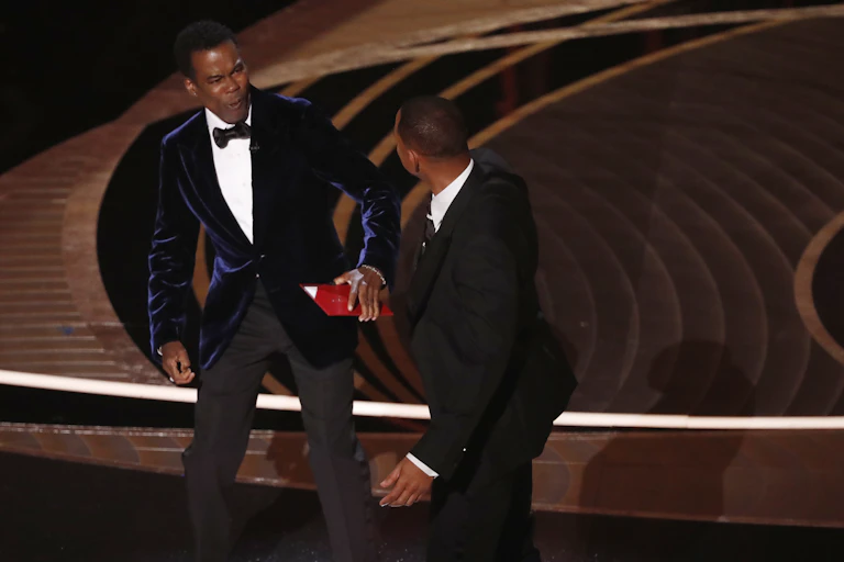 Two men in suits on stage.