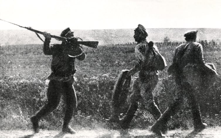 Vintage photo of two Russian deserters being threatened by another solduer with a rifle.