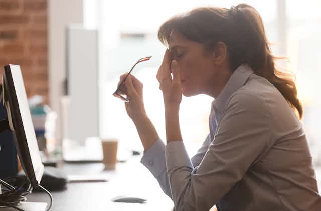 Woman looking tired at office work station.