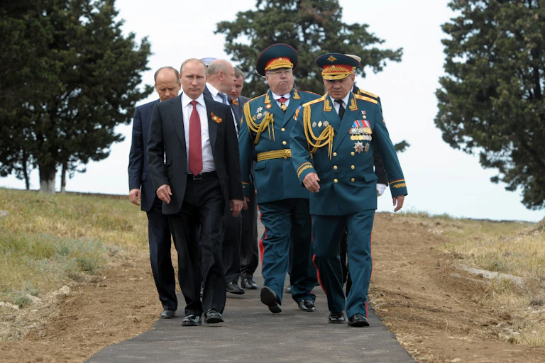 Vladimir Putin walks in the country with a grou pf military officers and intelligence staff.