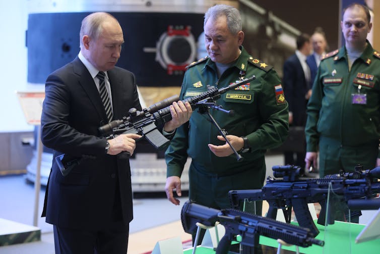 Russian president Vladimir Putin looks at a rifle with Russia's defence minister, Sergei Shoigu