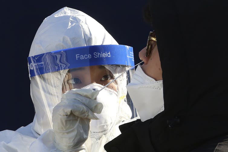 A medical worker takes samples from a man during COVID-19 testing at a makeshift clinic.