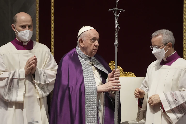 Pope Francis wearing a purple robe conducts a prayer service.