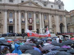 Crowds of people with black umbrellas gathered outside the Vatican.
