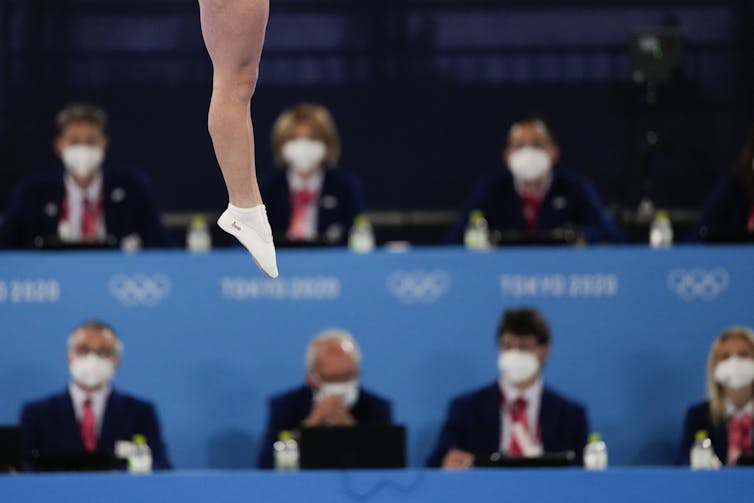 Feet are seen pointed in the air with judges sitting in the background.