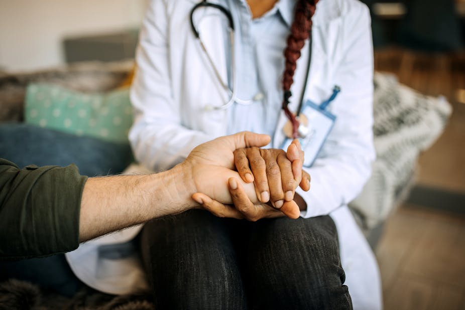 A female doctor holds the hand of a patient.