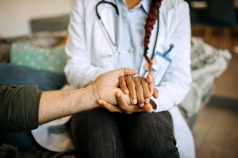 A female doctor holds the hand of a patient.