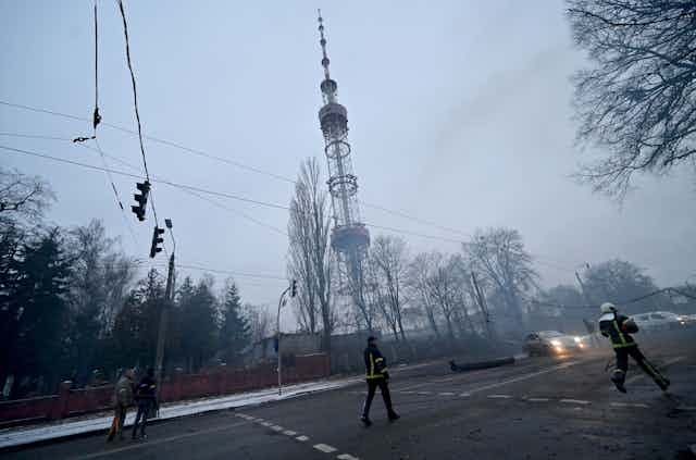 emergency services personnel on a hazy city street with a large telecommunications tower in the background