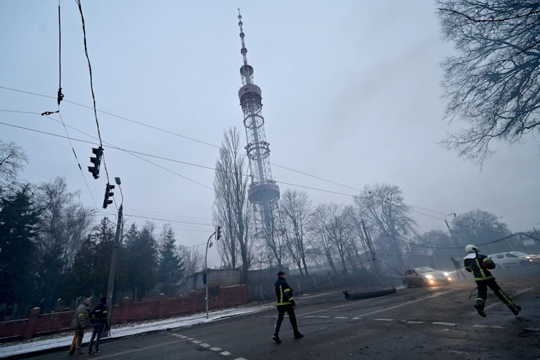 emergency services personnel on a hazy city street with a large telecommunications tower in the background