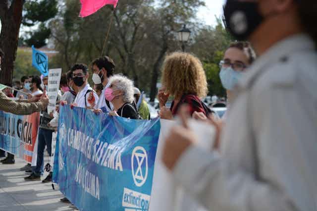 Un grupo de personas con mascarilla sostienen una pancarta