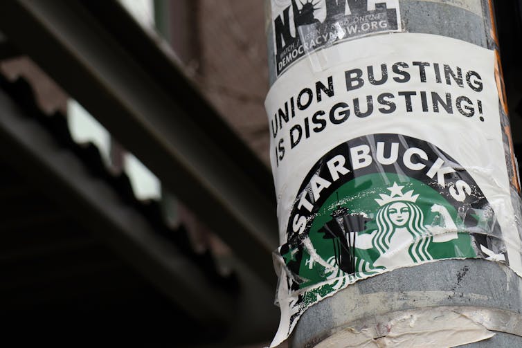 A pro-union poster is seen on a lamp pole says 'union busting is disgusting' over a Starbucks logo.