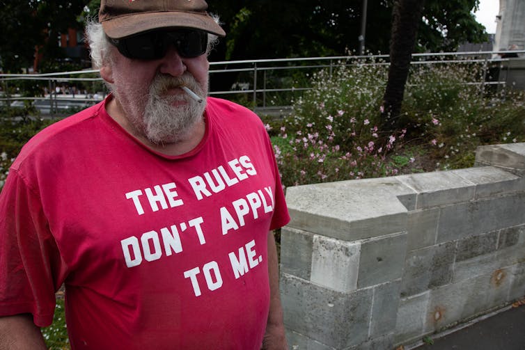 Man in red t'shirt that says'the rules don't apply to me'.