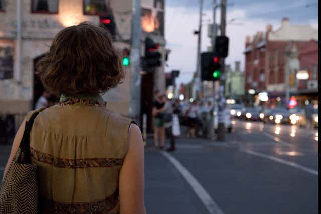 Woman walks down Melbourne street at twilight.