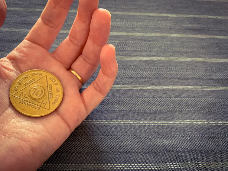 Hand with AA chip in the pam reading '10 month recovery'