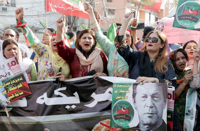 Protesters with red and green flags and photos of Imran Khan.