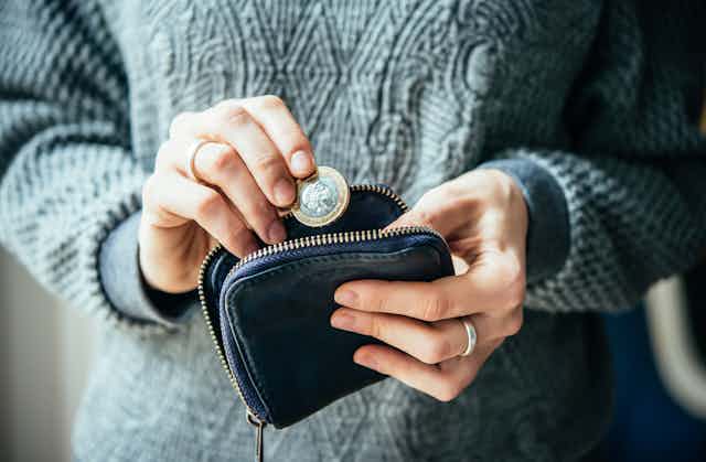 Hands removing a pound coin from a small purse