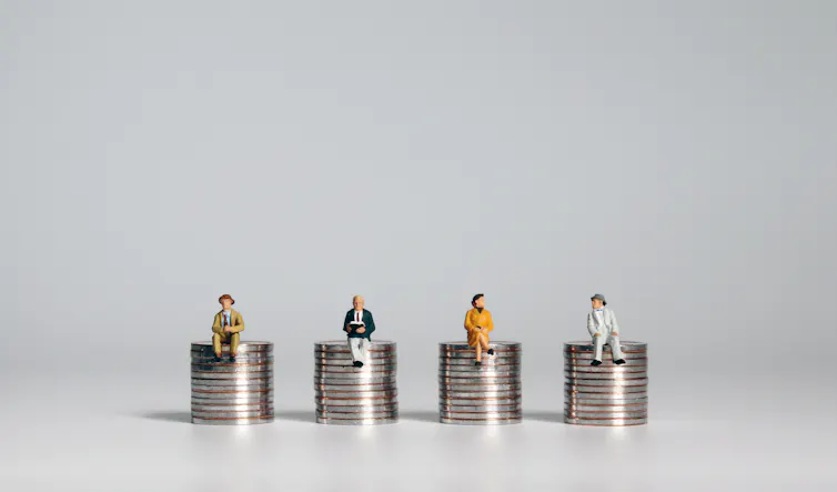 Four piles of coins with small figurines of people sitting on top of them.