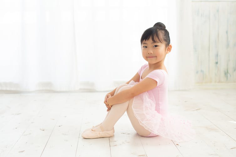 A child sitting in ballet wear.