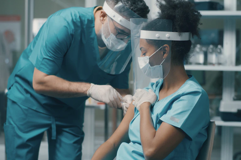 Health care provider administering vaccine to another health care provider