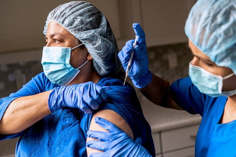 Health care provider administering vaccine to another health care provider