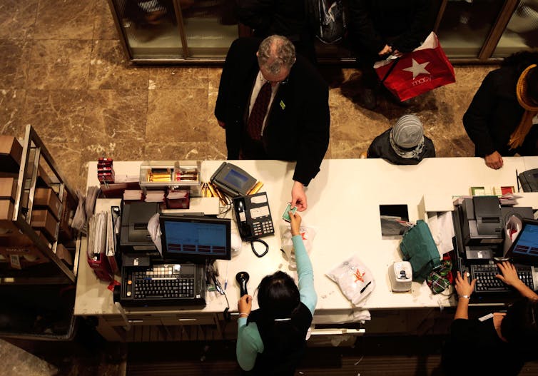 A man is seen using a credit card to purchase items from a cashier.