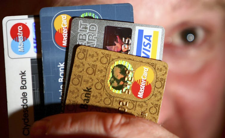 A man is seen holding several different credit cards in his hand.