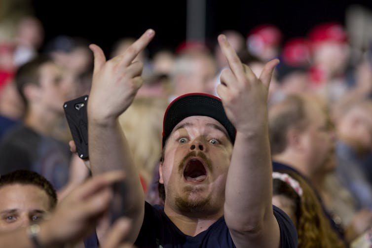 A man yells and raises both middle fingers