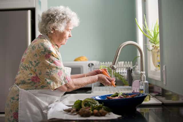 older woman at sink washing vegetables