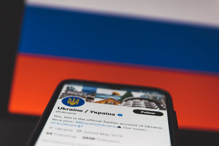 Mobile with Ukraine's Twitter account opened up held is in front of the Ukrainian flag