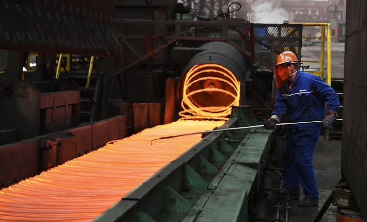 A man is seen making steel on a conveyor belt.