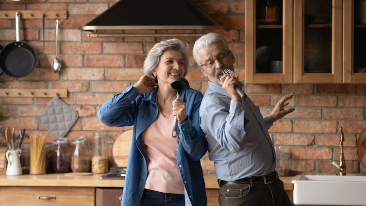 An older couple sing in the kitchen.